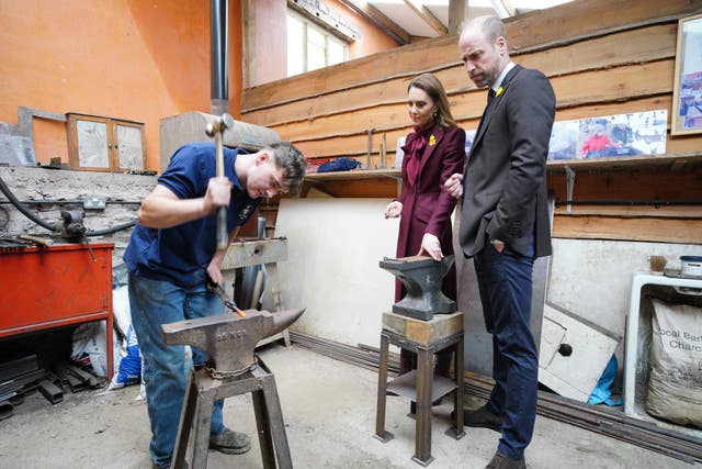 The Prince and Princess of Wales watching metal being forged during a visit to the Hanging Gardens