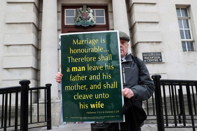 A man holds a placard quoting the Bible outside the Royal Courts of Justice in Belfast (Brian Lawless/PA)