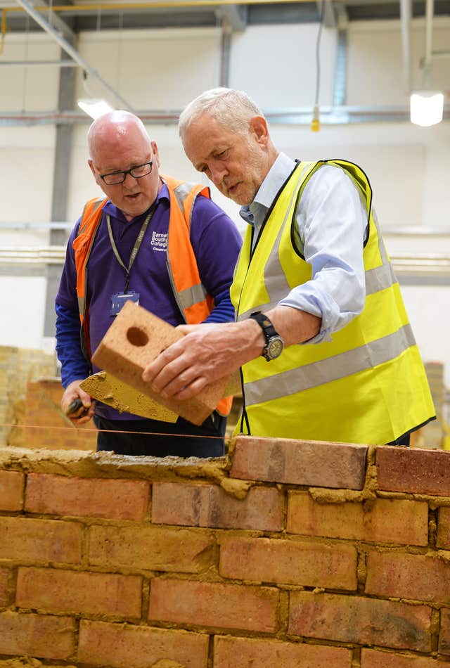 Labour leader Jeremy Corbyn has a go at bricklaying (John Stillwell/PA)