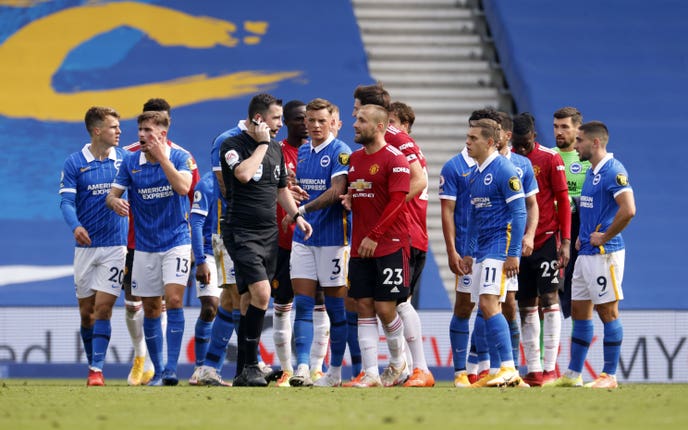 Chris Kavanagh is surrounded by players in the final moments of the game as he checks a VAR penalty decision which resulted in Manchester United’s Miguel Bruno Fernandes scoring the winning goal during the Premier League match at the AMEX Stadium