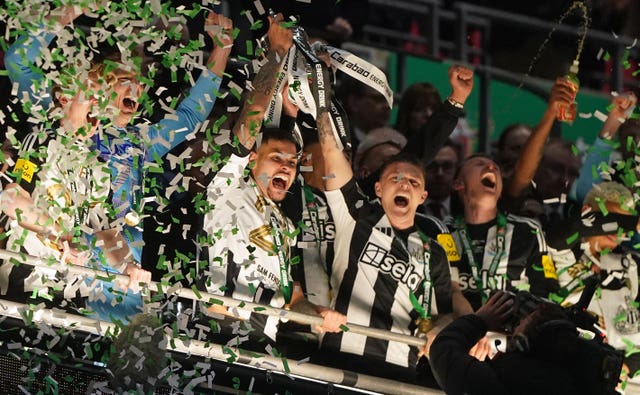 Newcastle United’s Bruno Guimaraes (centre left) and Kieran Trippier lift the trophy after winning the Carabao Cup