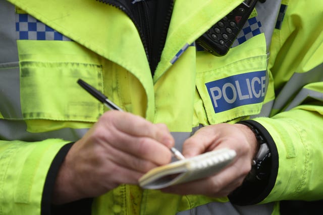Close-up of a police officer in hi-vis writing on a notepad