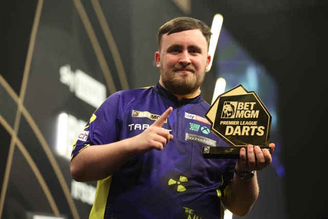 Luke Littler holds his trophy