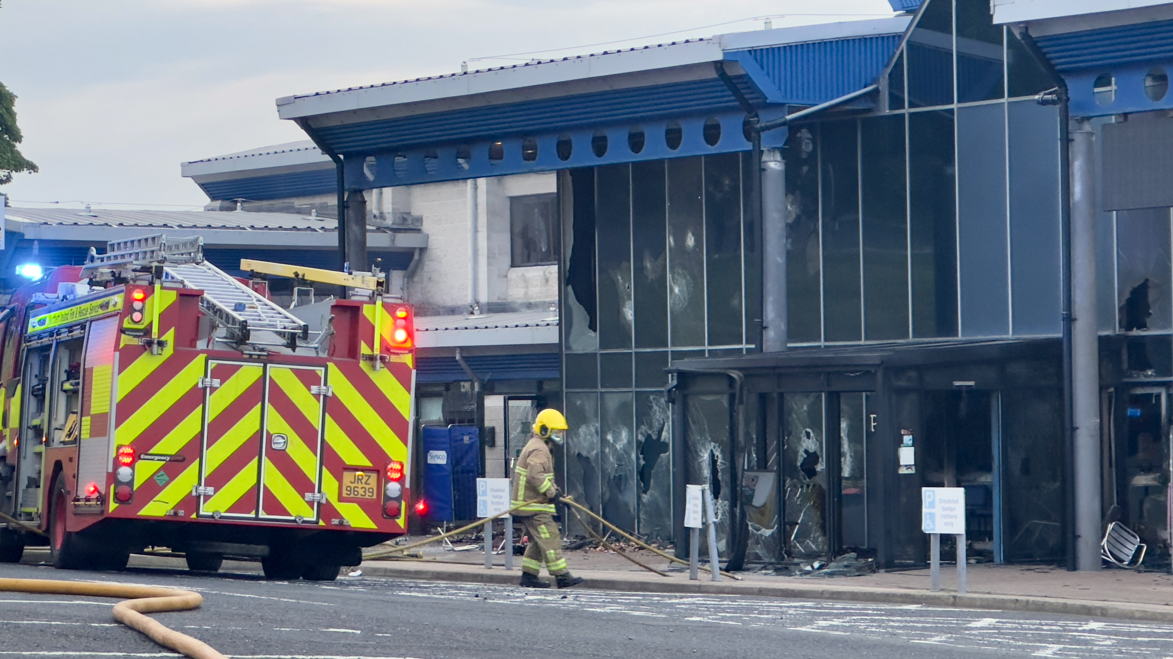 Firefighters outside a glass-fronted building which has been vandalised