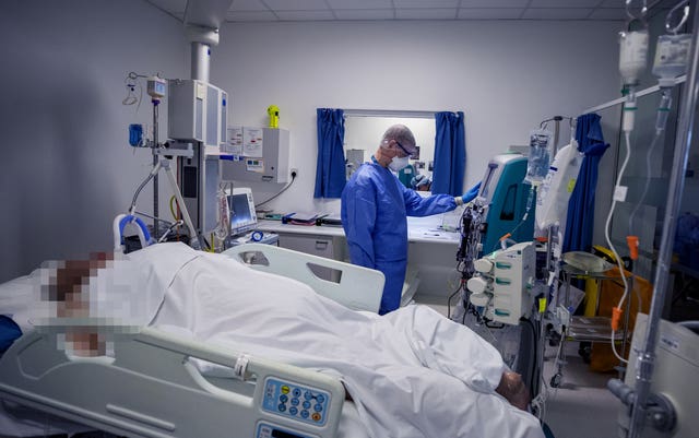 A health worker tends to a patient on an ICU