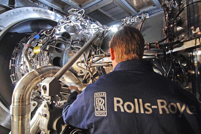 A worker in Rolls-Royce overalls working on an engine in a factory