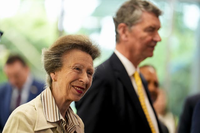 Princess Royal smiling, with her husband Vice Admiral Sir Tim Laurence in the background