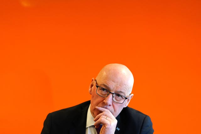 John Swinney, with one hand resting on his face