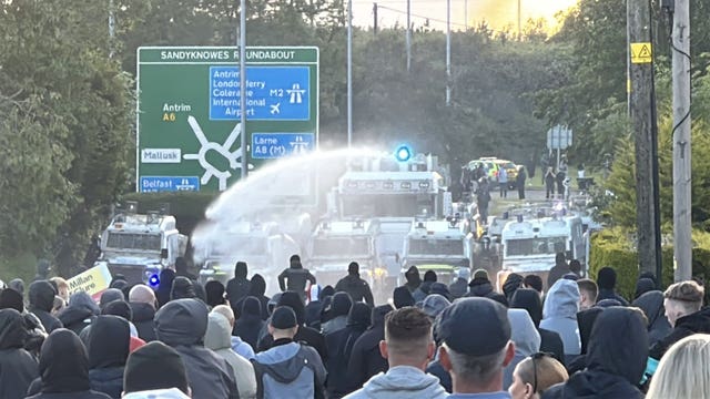 A water cannon is fired towards protesters on Antrim Road, at the Sandyknowes roundabout in Newtownabbey