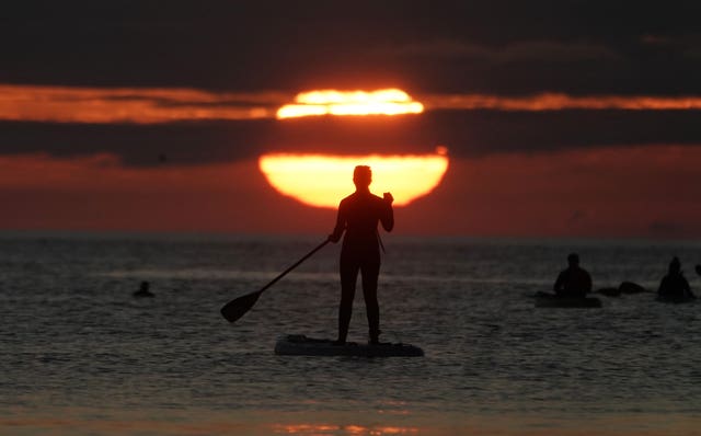 A paddleboarder watches the sunrise at Cullercoats bay in North Tyneside