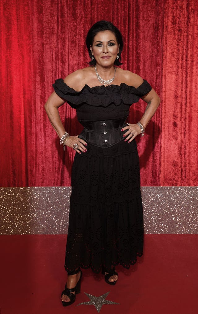 Jessie Wallace in black dress in front of red curtain