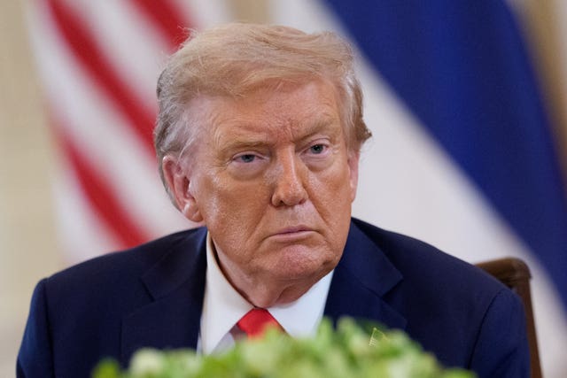 Donald Trump sits in front of a flag