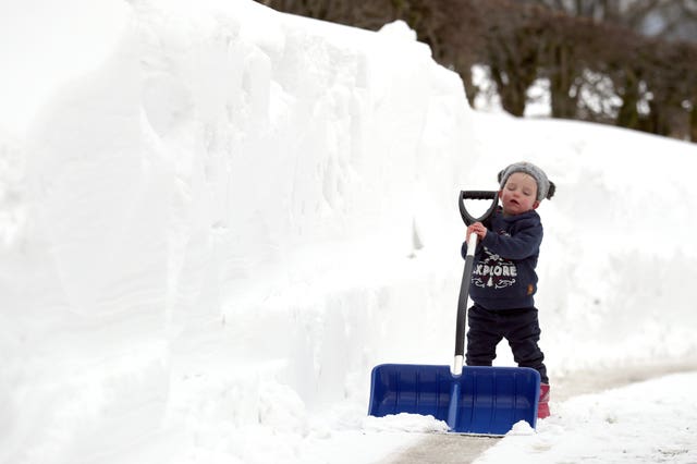 Amelie Muir helps her father Hector clear the snow in their driveway  (Andrew Milligan/PA)