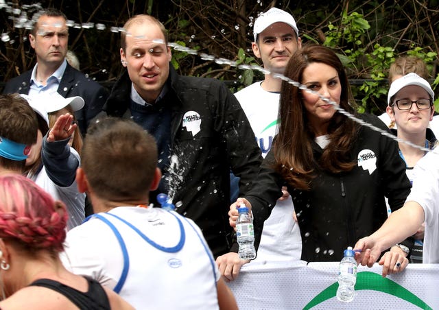The Duke and Duchess of Cambridge hand out water to runners during the 2017 London Marathon
