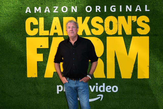A man stands in front of a billboard advertising Clarkson's Farm 