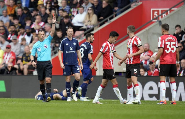Stuart Attwell raises a red card above his head as he sends off Southampton’s Jack Stephen against Manchester United, with Alejandro Garnacho on his back behind the referee after being fouled.