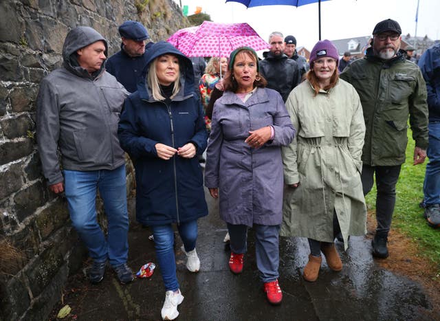 Michelle O'Neill and Mary Lou McDonald walk along a road in a group
