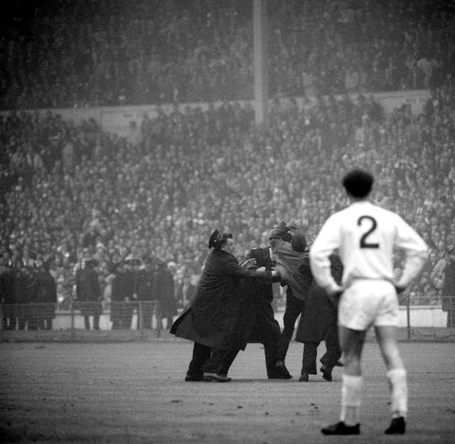 Leeds' Paul Reaney watches on as a Liverpool fan is apprehended for celebrating their winner
