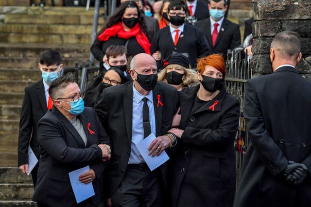 Husband and father David Lewis (centre) is helped out of church