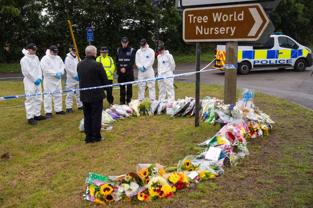 Police officers stand in silence at the scene