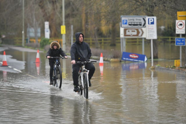 People riding their bikes through floodwater in Tewkesbury