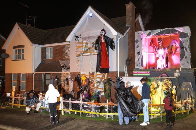 People pose and take pictures outside the Halloween display