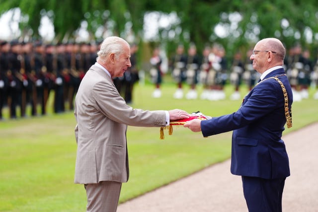 The King touching a red cushion, which is being held out by Edinburgh Lord Provost Robert Aldridge