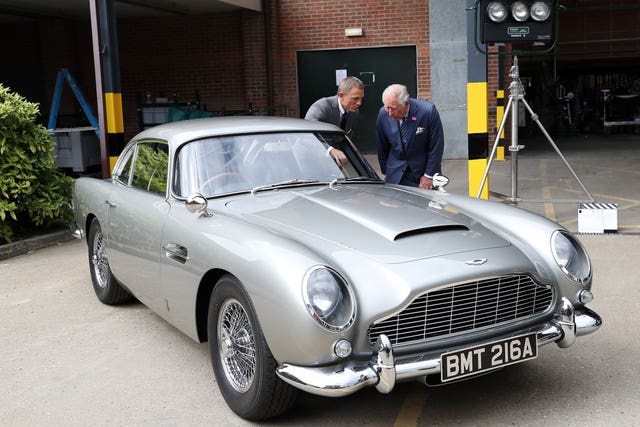 An Aston Martin DB5 with former James Bond Daniel Craig, as the King looks on