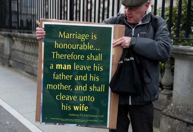 A man holds a placard quoting the Bible outside the Royal Courts of Justice in Belfast (Brian Lawless/PA)