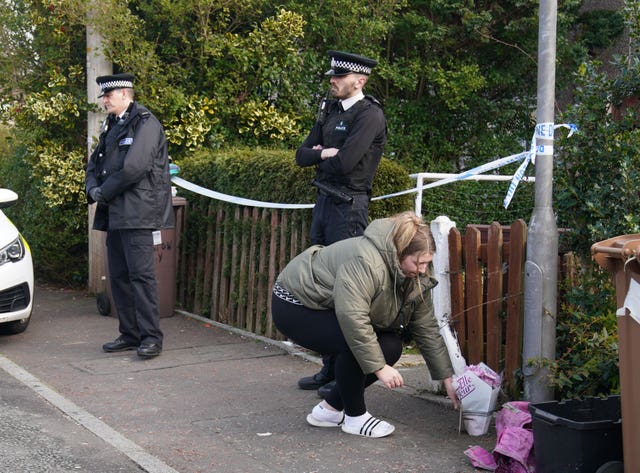 A woman lays flowers at the scene