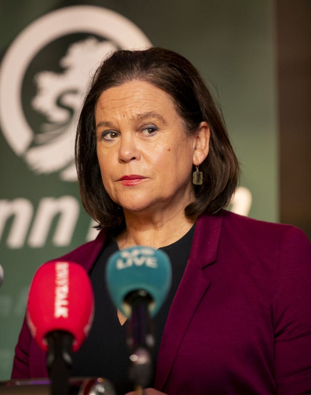 Dark-haired woman speaking into microphones