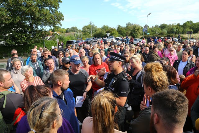 A police officer talks to members of the public gathered in Sandwich, Kent 