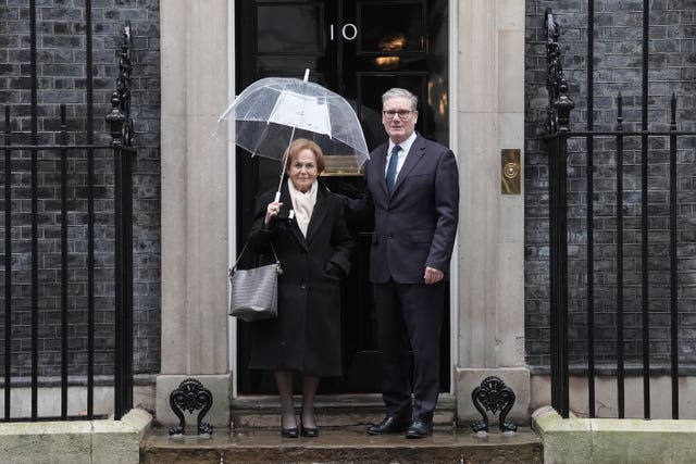 Prime Minister Sir Keir Starmer stands with Holocaust survivor, Mala Tribich, carrying an umbrella, on the steps of 10 Downing Street, London
