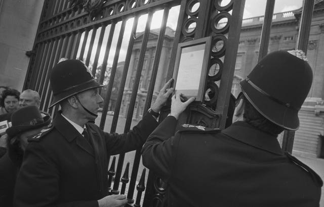 Policemen put up a bulletin signed by royal doctors on the gates of Buckingham Palace after the birth of Princess Anne’s first child in 1977 (PA)