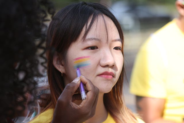 Pride volunteers add rainbow face paint to each other’s faces