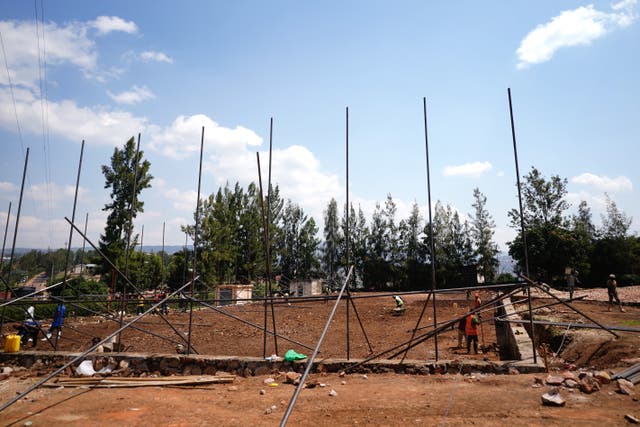 Construction workers shovel earth on the site of a basketball court that will be built next to the Hope Hostel