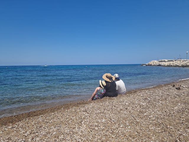Toni-Claire Miller sitting on a beach with her children