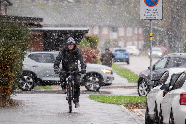 A person cycles through snowfall in Crawley