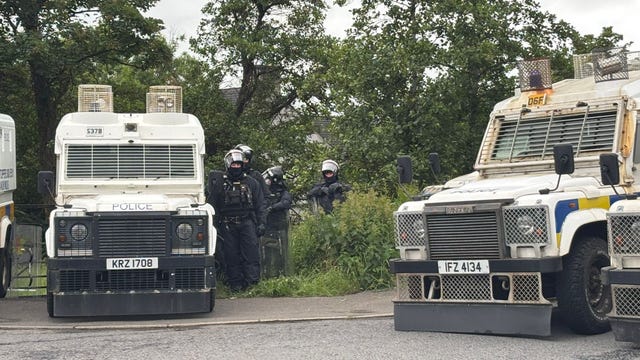 PSNI officers in riot gear with armoured vans monitor protesters in Scarva