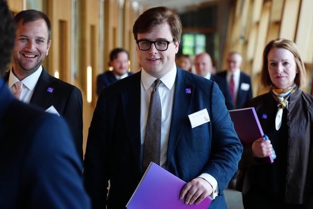 Max Bannerman smiling while walking through a corridor at Holyrood