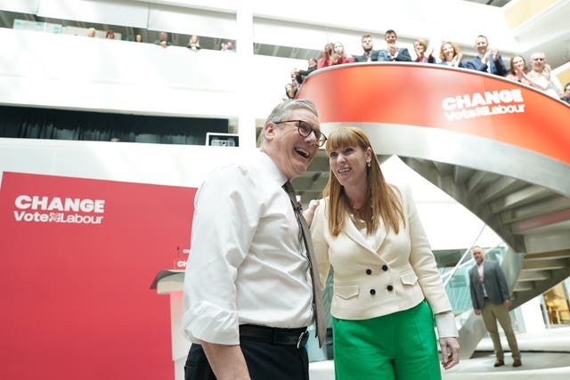 Labour leader Sir Keir Starmer and deputy Angela Rayner stand together smiling, with colleagues looking on from above, after the launch of the party manifesto