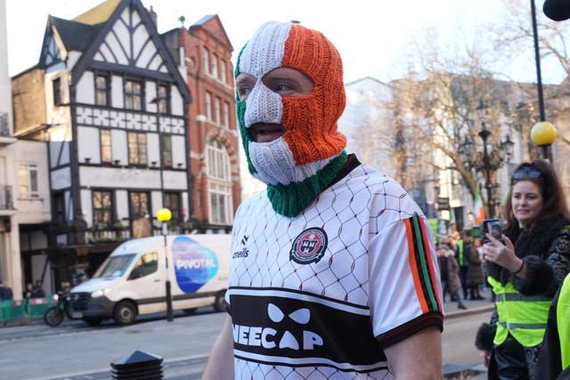 JJ O’Dochartaigh wearing a Kneecap T-shirt and a red, orange and green striped balaclava