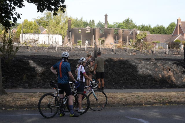 People looking at the remains of burnt-out houses
