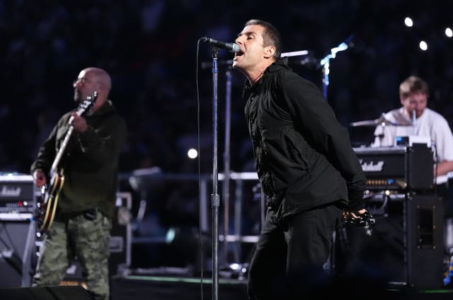 Liam Gallagher singing into a microphone on stage