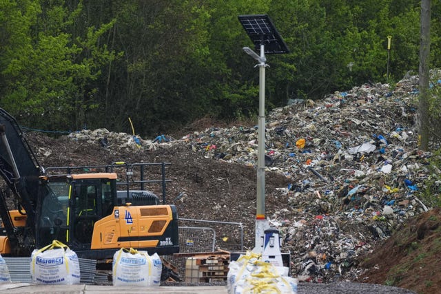 A digger in front of the mountain of illegal waste