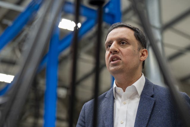 Anas Sarwar speaking, with a view of a warehouse behind him