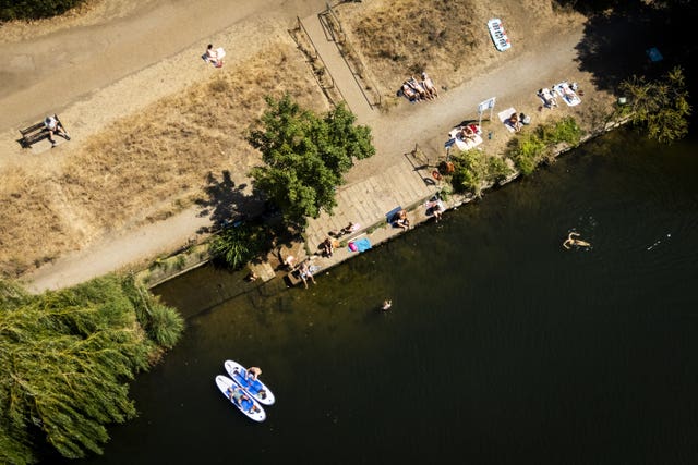 People sunbathing and swimming in the water at the Thames at Ham