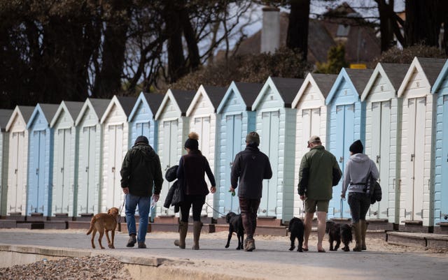 A bracing walk past beach huts on Avon beach in Mudeford, Dorset