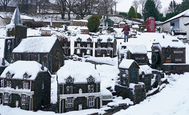 Lawson Robinson clears snow from his Nenthead miniature village in Cumbria after Storm Freya hit Britain