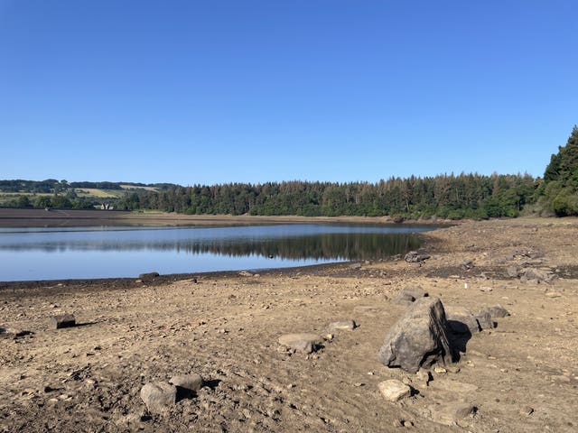 Bare ground exposed by low water levels at Yorkshire Water’s Agden Reservoir, near Sheffield, under a bright blue sky.